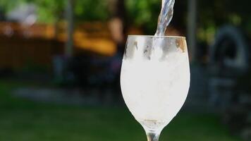 versare limonata con ghiaccio ghiaccio in un' bicchiere versare bibita acqua gettare Limone agitare con un' cannuccia parecchi video di un' freddo bevanda su il strada su il tavolo spumeggiante schiuma bolle avvicinamento