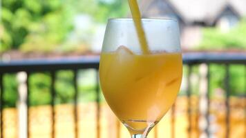 Close-up of me stirring the pulp in the orange juice, in slow motion. Orange juice in a transparent glass filled with ice cubes video