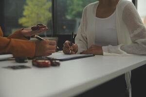 Insurance officers hand over the car keys after the tenant. have signed an auto insurance document or a lease or agreement document Buying or selling a new or used car with a car photo