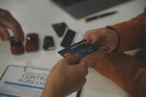 auto business, sale and people concept - close up of customer giving credit card to car dealer in auto show or salon photo