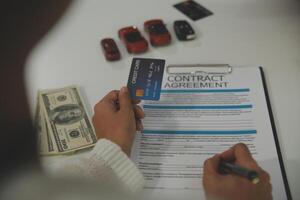 auto business, sale and people concept - close up of customer giving credit card to car dealer in auto show or salon photo