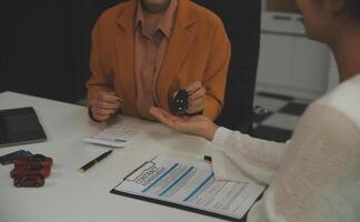 Insurance officers hand over the car keys after the tenant. have signed an auto insurance document or a lease or agreement document Buying or selling a new or used car with a car photo