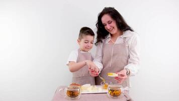 Mama und wenig Sohn Verbreitung auf Käse Honig Frühstück gesund Essen auf ein Weiß Hintergrund trinken Tee Küche Schürze video