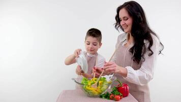 mãe ensina filho para cozinhar salada Garoto acrescenta amarelo Pimenta para vidro prato aprende para cozinhar delicioso saudável vegetariano Comida vitaminas benefícios família lazer video
