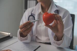 Hands of doctor woman holding red heart, showing symbol of love, human support to patient, promoting medical insurance, early checkup for healthcare, cardiologist help. Close up of object photo