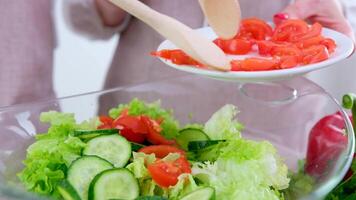 vrouw in de werkwijze van voorbereidingen treffen gezond voedsel groente salade menging salade houten lepel in keuken Bij huis dieet concept. video