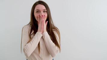 surprise joy the girl covered her face with her hands laughing joyful eyes the girl looks into the frame laughing smiling long hair white background pleasant emotions positive video