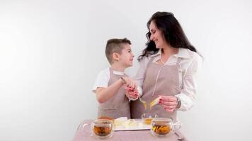 mom and little son spread on cheese honey breakfast healthy food on a white background drink tea kitchen apron video