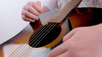 kaukasisch Junge 6 Jahre alt Sitzung auf das Couch Theaterstücke das akustisch Gitarre. das Junge lernt zu abspielen das Gitarre während beim heim. Freizeit beim Zuhause mit ein Gitarre, ein Kinder Leidenschaft zum Musik- video