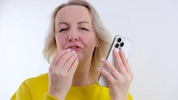 woman in orange clothes showing thumbs up smiling laughing blowing kiss in other hand phone video