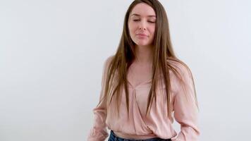 söt flicka med lång hetero hår i en rosa blus på en vit bakgrund i de studio slickar henne mun leende poser för en Foto skjuta Plats för text reklam skönhet personlig vård video
