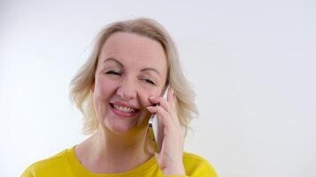 Young adult caucasian woman is typing on her smartphone on a bright yellow background video