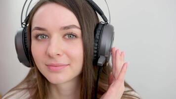 retrato do adorável Adolescência menina vestindo fones de ouvido. atraente aluna sorridente fechar acima. video