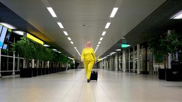 en arrivant ou départ à aéroport femme avec valise sur roues dans mains main bagage la communication attendre nuit à l'extérieur fenêtre marcher vers le bas couloir âge moyen blond réel gens Amsterdam aéroport video