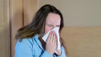 ziek allergisch jong vrouw niezen in zakdoek blazen rennen neus. ziek meisje kreeg griep concept of gevangen koud, hebben allergie symptomen. ongezond dame lijden van seizoensgebonden virus ziekte. dichtbij omhoog visie video