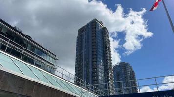 skytrain Pare dentro Vancouver estádio Chinatown estação pessoas entrar a skytrain azul céu com nuvens arranha-céus a bandeira do Canadá vibra dentro a vento video