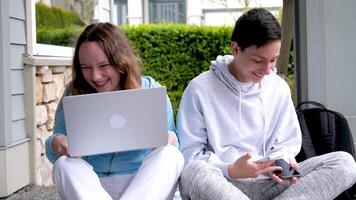 nett zu tun Hausaufgaben zusammen mit ein Freund Jungs Mädchen Sitzung auf das Veranda Laptop Aktentasche Mappe draußen Zuhause Turnschuhe Sportbekleidung angenehm Beziehung zuerst Liebe Klassenkameraden Jugendliche Jugend video