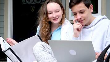 sit outside on porch whisper in ear have fun laugh doing homework boy and girl heterosexual friends teenager using laptop and tablet for online schooling from home together, quarantine concept. video