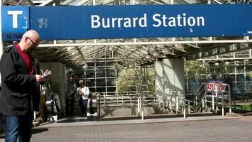 burart station skytrain station a man looks at geolocation choosing where to go an adult bald man in glasses travels looking for a way home people on an escalator leave station cherry blossoms video