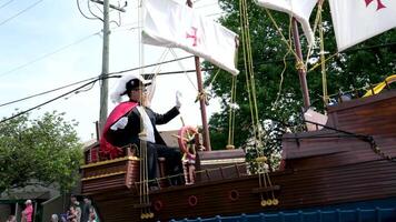 trébol un pirata Embarcacion pasa a lo largo el calle durante un gay desfile hombres en batas aleteo en el viento un sombrero con un pluma machos en trajes y chaquetas de el mayor blanco guantes lentes Embarcacion por coche video