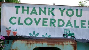 old rusty truck with the inscription Thank you cloverdale painted with carrots and flowers hats people celebrating gay parade procession passes through main street children and adults freedom video