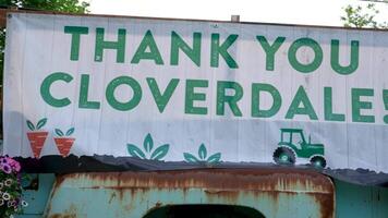 old rusty truck with the inscription Thank you cloverdale painted with carrots and flowers hats people celebrating gay parade procession passes through main street children and adults freedom video