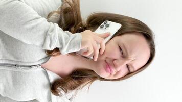 yawn while talking on phone an unpleasant boring conversation young girl covers mouth with hand yawns teenager tired of resting on white background white phone contorts face in dissatisfied mug video