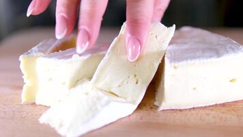 composição do italiano queijo, em uma de madeira corte borda. 1 mão leva a faca e rompe uma casal do peças para saborear a qualidade. video