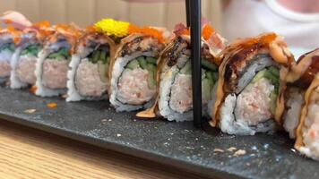 negro continuar rodar carne de cangrejo, palta, kappa dentro con unagi, palta, pescado copos y pescado tomar un pedazo de Sushi rodar con negro palillos video