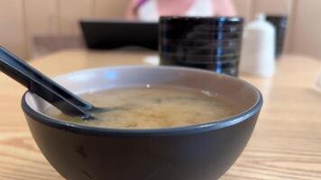 missô sopa com tofu e algas marinhas dentro Castanho japonês tigela quente Comida vapor sobre prato lento movimento restaurante Ásia video