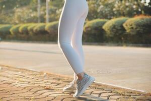 Young fitness woman runner stretching legs before run on city photo