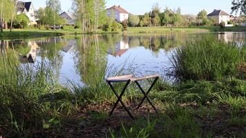 Fischer Stuhl auf Hintergrund von See. Natur und Hobby. Frühling sonnig Morgen im Dorf. video