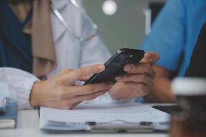 consulta en línea. irreconocible médico utilizando teléfono inteligente a lugar de trabajo, mensajería con paciente, prescribir tratamiento foto