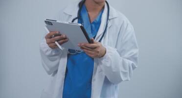 Woman doctor using tablet computer while standing straight in hospital photo