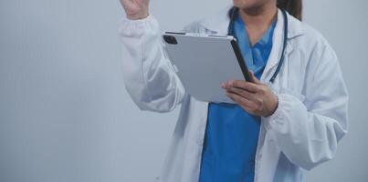 Woman doctor using tablet computer while standing straight in hospital photo