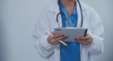 Woman doctor using tablet computer while standing straight in hospital photo