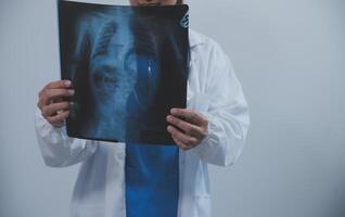 Asian Muslim doctor in hijab and scrubs headphones around her neck Stand confidently in the medical office, isolated on white background, holding x-ray film. photo