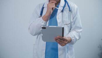 Mature male doctor with tablet pc is giving presentation. Blurred background indoors. photo