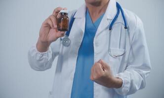 Portrait of young Asian male doctor smiling, showing a Medicine bottle and looking by Confident while standing Friendly and kind in the hospital. Healthcare and medical insurance concept. photo