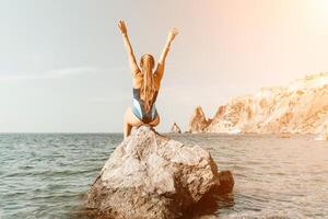 Woman travel summer sea. A happy tourist in a blue bikini enjoying the scenic view of the sea and volcanic mountains while taking pictures to capture the memories of her travel adventure. photo