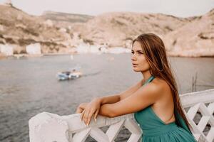 Woman sea green dress. Side view a happy woman with long hair in a long mint dress posing on a beach with calm sea bokeh lights on sunny day. Girl on the nature on blue sky background. photo