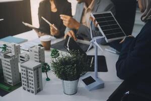 verde energía negocio empresa reunión con negocio personas planificación y discutir márketing de sostenible y renovable limpiar energía producto con solar célula y viento turbina generador. pionero foto