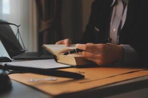 Business and lawyers discussing contract papers with brass scale on desk in office. Law, legal services, advice, justice and law concept picture with film grain effect photo