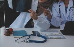 Doctor discussing diagnosis during the meeting. Group of doctor discussing work matter in the office at work. The medical team discusses treatment options with the patient. photo