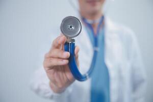 Senior doctor wearing white coat standing holding stethoscope in hands. Older male physician healthcare professional showing medical equipment ready to listen lungs or heart concept. Close up view photo