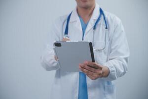 Mature male doctor with tablet pc is giving presentation. Blurred background indoors. photo