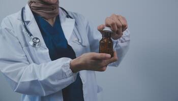 Southeast Asian medical doctor holding a bottle of pills, smiling isolated white background photo