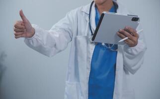 Woman doctor using tablet computer while standing straight in hospital photo