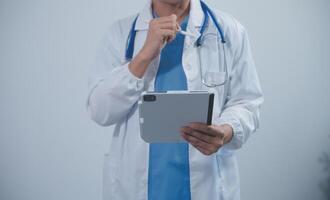 Mature male doctor with tablet pc is giving presentation. Blurred background indoors. photo