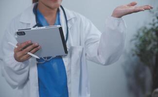 Woman doctor using tablet computer while standing straight in hospital photo